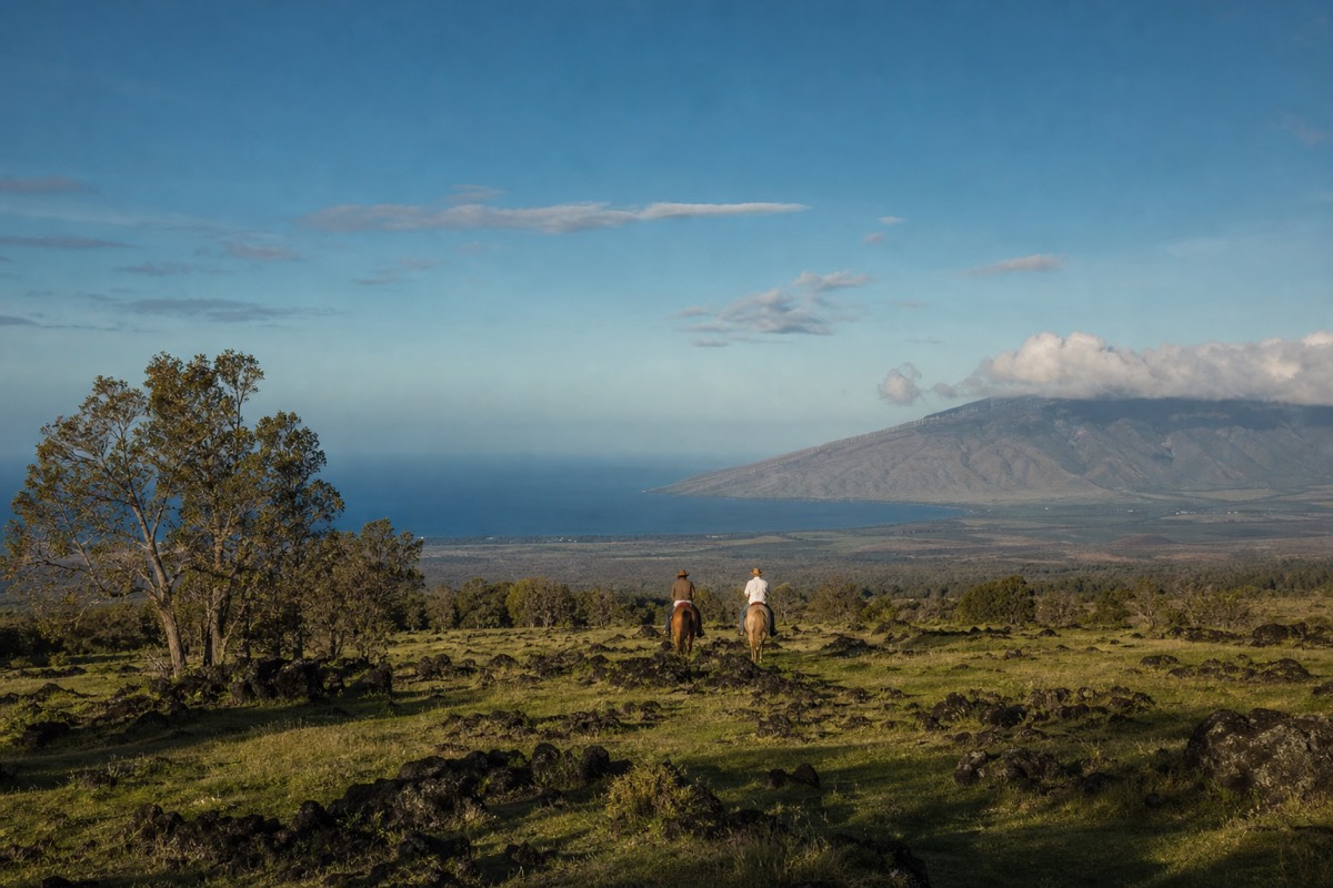 Horseback rider on the Maha'ulepu Heritage Trail overlooking Kauai's coast and green mountains